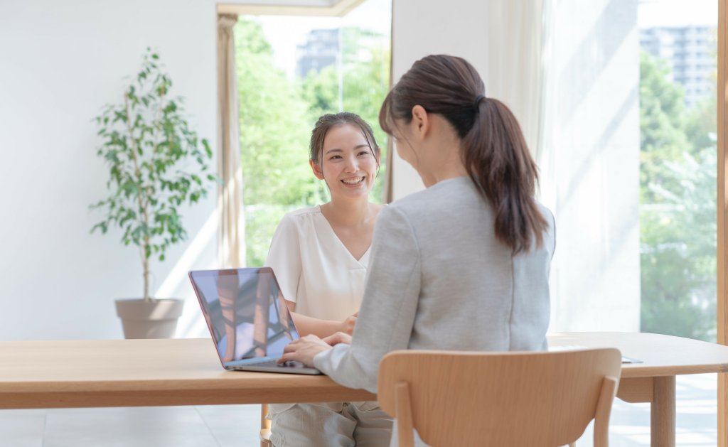 PCを触る女性と笑顔の女性