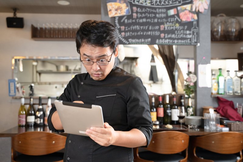 タブレットを見て驚く男性 レストラン