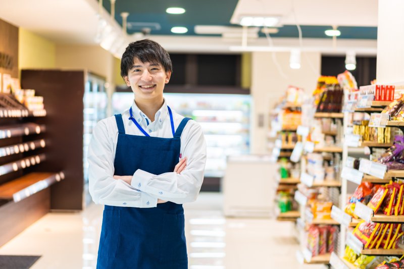 店内で腕を組み笑顔のスーパーの店員